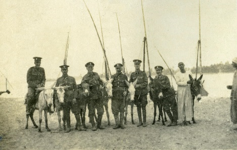 Soliders with donkeys in front of boats on the banks of the Nile river
